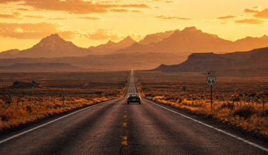 Scenic open road through the American West with mountains and golden sunset — best road trips USA